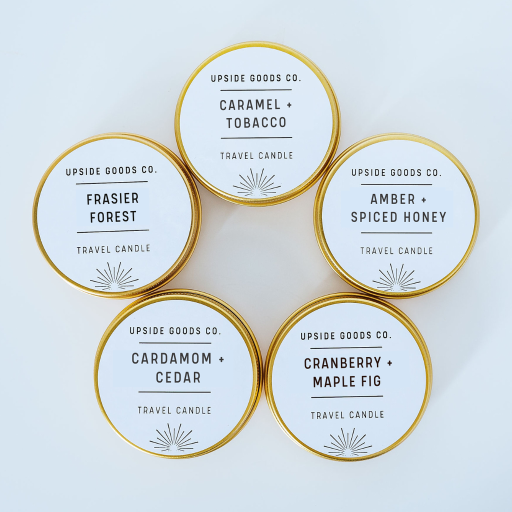 Set of gold holiday travel candles with labels on a light blue background
